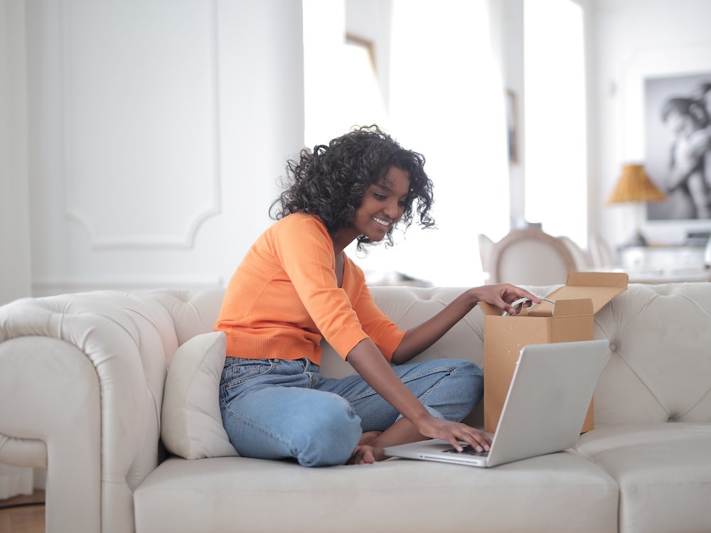 a person sitting on a couch with a laptop and a box